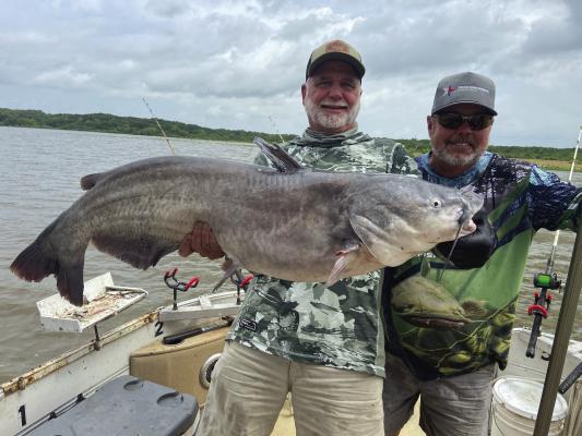 Jeff Rice, left, and Lake Tawakoni catfish guide Tony Pennebaker show off a giant blue catfish landed from shallow water last week. Photo by Luke Clayton