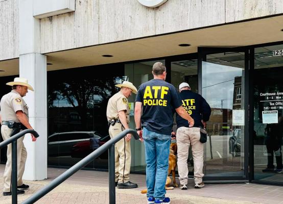 Henderson County Sheriff Botie Hillhouse (from right) and Henderson County Judge Wade McKinney, along with other Henderson County officials, wait outside the Henderson County courthouse in downtown Athens after multiple bomb threats forced evacuations during their weekly Commissioners’ Court meeting June 7. Photo by Jody Vincik