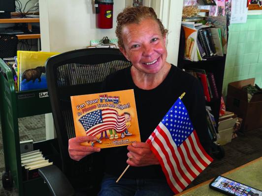 Grand Saline Public Library Librarian Brandi Collard is shown with one of the U.S. Flag children’s books donated by DAR. Courtesy photo