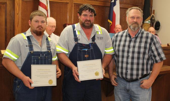 Van Zandt County Pct. 1 employees Brandon Holland (far left) and Derek Koonce were recognized for their recent efforts in rendering aid to a VZC citizen by the VZC Commissioners Court. Presenting Holland and Koonce to those in attendance was VZC Pct. 1 Commissioner Chad LaPrade. See story on 2A. Photo by David Barber