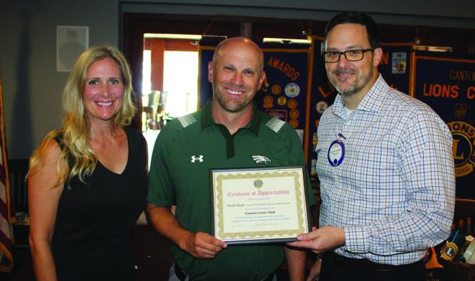 A ‘Certificate of Appreciation’ was presented to Canton High School Athletic Director and Head Football Coach Heath Ragle Aug. 28 following Ragle’s guest speaking appearance at the weekly luncheon of the Canton Lions Club. Standing with Ragle were his wife, Ashley, and Canton Lions Club President Jonathan Helvey. Photo by David Barber
