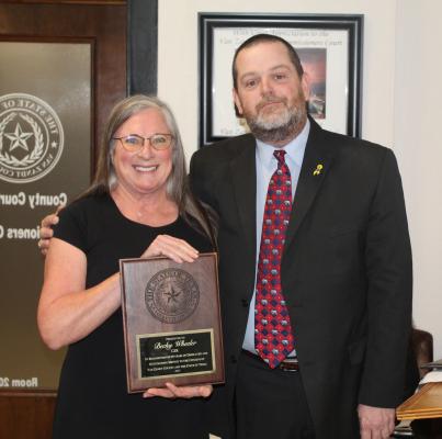 Retiring Van Zandt County Court Reporter Becky Wheeler was presented with an appreciation plaque for her 40 years of service by VZC County Court at Law Judge Josh Wintters March 26 during the regular meeting of the VZC Commissioners Court. Photo by David Barber