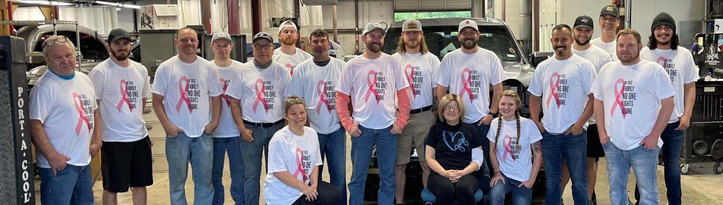Family and employees at Canton Paint and Body pose with Sue wearing matching shirts reading ‘In this family, no one fights alone.’ Courtesy photo