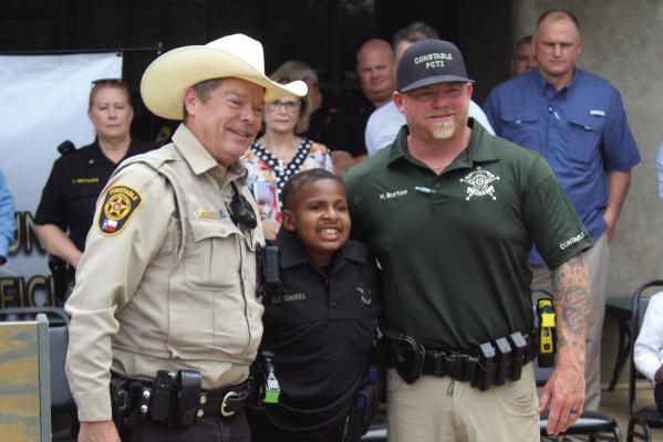 Van Zandt County Pct. 3 Constable Jeff Caughron, left, and VZC Pct. 2 Constable Heath Burton previously made 13-year-old DJ Daniel an Honorary VZC Constable prior to Daniel being named as an Honorary VZC Sheriff’s Department Deputy April 4 during a special ceremony in front of the VZC Sheriff’s Department Office. Photo by David Barber