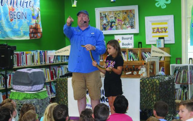 A young volunteer assisted Eric Brittingham, known as ‘Mr. B,’ as he answered a question from the audience about snakes June 28 during a ‘Wildlife on the Move’ program at the Van Zandt County/Sarah Norman Library in Canton. The ‘Wildlife on the Move’ presentation was part of the weekly Summer Reading Program series at the library. The Summer Reading program continues every Friday at 10 a.m. through the end of July. Photo by Susan Harris