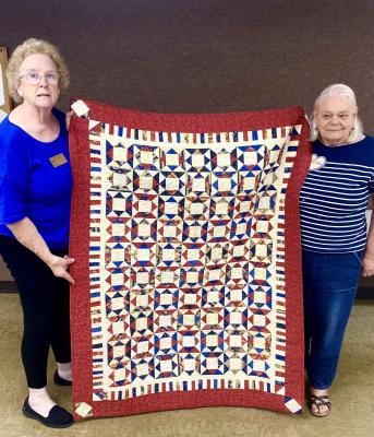 Suzanne DiCarlo, along with a member of the Quilts of Valor foundation, displays a quilt made at the Texas Star Quilters Guild meeting on Monday, Sept. 19. Photo by Ethan Adams